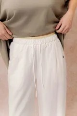 Pantalón de pierna recta color blanco off-white, de calce amplio y fluido. Posee cintura elastizada con cordón regulable y bolsillos laterales funcionales.
