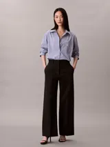Camisa Calvin Klein de corte regular, con diseño de rayas verticales en tonos azul y blanco. Cuenta con cuello camisero, cierre frontal de botones, mangas largas y un bolsillo aplicado en el pecho con el logo bordado de la marca.