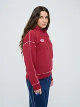 Canguro deportivo Umbro del Club Nacional de Football, color bordó, con capucha ajustable con cordón, bolsillo tipo canguro y costuras visibles en contraste. Presenta el logo de Umbro y el escudo del club bordados en el frente.