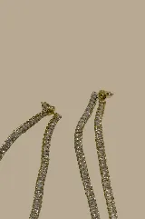 Caravanas largas doradas con doble tira de cristales brillantes, una tira queda por delante y otra por detrás de la oreja.