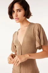 Vestido largo dorado de punto con mangas cortas con volantes, escote en V y cierre frontal con botones.