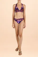 Bombacha de bikini con diseño tipo corset, caracterizada por una faja ancha cruzada en la cintura. Presenta un estampado botánico con hojas en tonos púrpuras y cobrizos, con un corte en V que estiliza la figura.