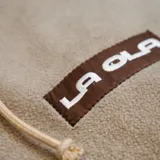 Canguro de polar color marrón con capucha, cordones de ajuste y bolsillo frontal tipo canguro. Presenta un pequeño parche rectangular con el logo de la marca en el pecho.