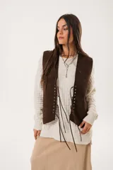 Chaleco marrón de gamuza con cordones laterales y tachas plateadas.