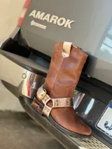 Bota de cuero marrón con estribo desmontable plateado.