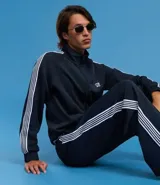 Campera deportiva de cuello alto con cierre frontal completo, mangas largas con rayas laterales blancas contrastantes y bolsillos laterales. Presenta un bordado pequeño en el pecho.