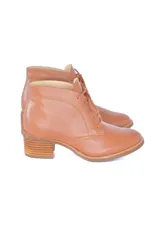 Botines de cuero vacuno color caramelo con diseño clásico de caña baja, cordones frontales y puntera redondeada. Presentan un tacón bloque texturizado de altura media.