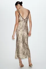 Vestido midi de estilo lencero con estampado animal print, confeccionado en tejido satinado. Presenta escote en pico tanto en el delantero como en la espalda y cuenta con doble tirante fino en color negro.