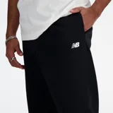 Pantalón de jogging New Balance de hombre, modelo MP41519BK, confeccionado en tejido French Terry negro. Cuenta con logo bordado, bolsillos con cremallera, bolsillo trasero con cremallera, bajo inferior elástico y cordón de ajuste interno.