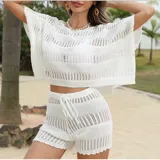 Conjunto de dos piezas tejido en punto calado color blanco, compuesto por una blusa de corte holgado con cuello redondo y mangas cortas, y un short de tiro medio con cintura elástica ajustable mediante cordón.