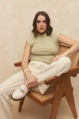 Top negro sin mangas con cuello alto y fruncido en los laterales. Es elastizado y cuenta con un botón a tono en la espalda.