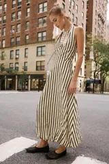 Vestido midi de cuello halter anudado, escote en pico y espalda descubierta, con diseño a rayas verticales y bajo abullonado con elástico interior.
