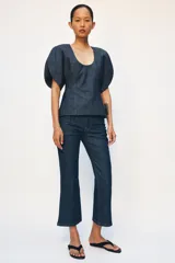 Blusa de Zara confeccionada en mezcla de algodón con acabado denim. Presenta escote redondo, mangas cortas abullonadas con volumen y costuras con pespuntes a contraste. Cierre posterior con cremallera oculta.