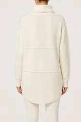 Polera de cuello alto con diseño oversize, manga larga y dobladillo asimétrico con corte redondeado en la parte frontal.