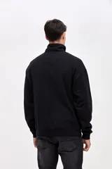 Buzo de felpa con friza, color negro, con cuello alto y cierre frontal parcial. Presenta bordado de la marca en el pecho y un calce relajado.