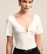 Blusa de manga corta confeccionada en tejido de viscosa texturizado, con escote en V profundo que presenta un detalle de aro metálico central.