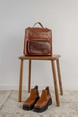 Botas tipo chelsea de caña baja, confeccionadas en una combinación de cuero gamuzado y cuero texturizado en tono marrón oscuro. Presentan una suela track de plataforma gruesa y elásticos laterales negros.