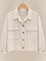 Sobrecamisa de lino color beige, de corte holgado, con cuello camisero, cierre frontal de botones carey y bolsillos frontales con solapa. Presenta mangas largas con puños abotonados.