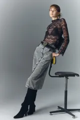 Falda midi de denim rígido con lavado gris, presenta cierre frontal con botones metálicos grabados y diseño de recortes verticales en el frente.