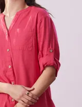 Blusa color rosa de lino marca Cupio, con cuello a la base, escote en V y abertura con botones. Tiene un bolsillo en la parte delantera y mangas 3/4 regulables con presilla y botón.