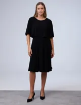 Vestido midi negro con corte a la rodilla, de seda fría, con capa superior superpuesta y mangas cortas.