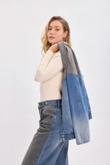Campera de jean con diseño bicolor, combinando paneles en color gris oscuro y azul denim. Presenta cuello camisero, cierre frontal con botones metálicos y corte holgado.