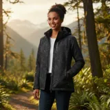Campera cortaviento impermeable de la marca Uniteduy, color negro con estampado sutil de hojas. Cuenta con capucha, cierre frontal, tres bolsillos externos y uno interno. Es una prenda ultra liviana y transpirable, ideal para actividades al aire libre.