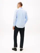 Camisa de algodón elástico con tejido dobby, color celeste claro, de corte slim, cuello con botones y puños redondeados con botón. Presenta el logo de Tommy Hilfiger bordado en el pecho.