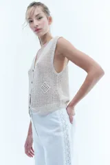 Pantalón blanco de lino de corte recto y pierna ancha, con detalle de puntilla en los laterales.