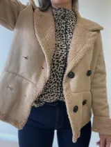 Chaqueta negra con forro tipo corderito, doble botonadura y cuello solapa.