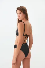 Bombacha de bikini tiro alto, confeccionada en tela con acabado satinado. Presenta un corte vedetina y cuenta con una etiqueta metálica con el logo de la marca en la parte posterior.