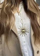Collar largo de bronce con dije en forma de sol con centro ovalado texturizado y rayos de diferentes medidas intercalados.