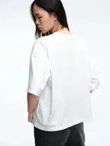 Remera de corte boxy y calce amplio, con cuello redondo y mangas cortas, de diseño minimalista y estructura relajada.