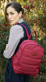 Mochila capitoneada color verde militar, confeccionada en nylon. Tiene apertura superior con cierre y tiradores metálicos, bolsillos internos, bolsillo frontal con cierre metálico, correa corta de mano y correas de galón regulables para colgar en la espalda.