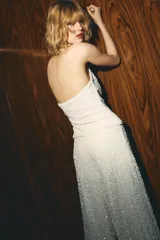 Top blanco con lentejuelas, cuello halter y escote fluido.