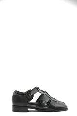 Zapato tipo cangrejera de cuero color marrón, con diseño de tiras entrelazadas, punta cerrada y pulsera con hebilla ajustable al tobillo. Cuenta con un taco bajo de madera.