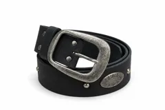 Cinturón de cuero negro con hebilla rectangular grande de metal plateado envejecido, tachas metálicas redondas y detalle de aplique ovalado grabado.