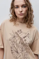 Remera negra de silueta amplia y calce relajado, con cuello redondo, mangas cortas con hombros caídos y estampa botánica en líneas blancas en el frente.