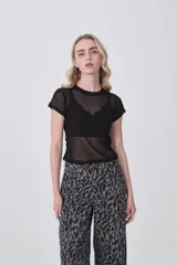 Remera de manga corta, cuello redondo y corte ajustado al cuerpo, confeccionada en poliéster con estampado abstracto en tonos grises y negros.