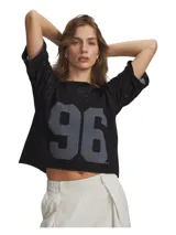 Remera Under Armour de corte holgado y estilo cropped, confeccionada en tejido de mezcla de algodón con efecto desgastado. Presenta un diseño con estampado frontal del número 96 en color gris, mangas cortas con detalle de transparencia y dobladillo inferior sin rematar.