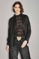 Camisa de cuero ovino color verde oliva, con cuello clásico, cierre frontal con botones y mangas largas con puños abotonados. Presenta un corte holgado y diseño tipo sobrecamisa.