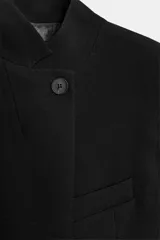 Blazer cropped de corte estructurado, con cuello subido, manga corta y cierre frontal con un botón. Presenta un bolsillo de vivo en el pecho y forro interior a tono.