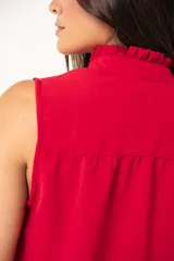 Camisa roja sin mangas con cuello mao adornado con un volado y cierre frontal con botones.