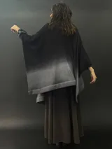 Ruana larga de lana merino color gris con cuello plisado de fieltro. Diseño degradado con terminación en flecos.