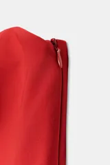 Top rojo sin tirantes, de escote recto y hombros descubiertos, con diseño ajustado en el torso y bajo acabado con peplum. Cierre lateral con cremallera oculta.
