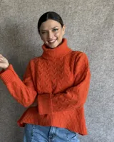 Sweater de lana color crudo con cuello alto y diseño trenzado.