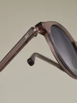 Anteojos de sol con armazón negro mate y forma redonda. Lentes con filtro degradado oscuro.