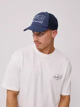 Gorro tipo trucker negro con visera curva y paneles traseros de malla. Estampado frontal en blanco con el logo de Rusty y el texto "RUSTY WORLDWIDE".