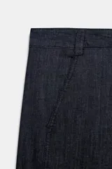 Pantalón de tiro medio con corte barrel, bolsillos laterales ocultos en costura y falsos bolsillos de vivo en la parte trasera. Presenta costuras laterales torcidas y cierre frontal con cremallera y botón.