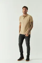 Remera polo color beige, de manga corta, con cuello y solapa de tres botones. Presenta un logo bordado en el pecho.